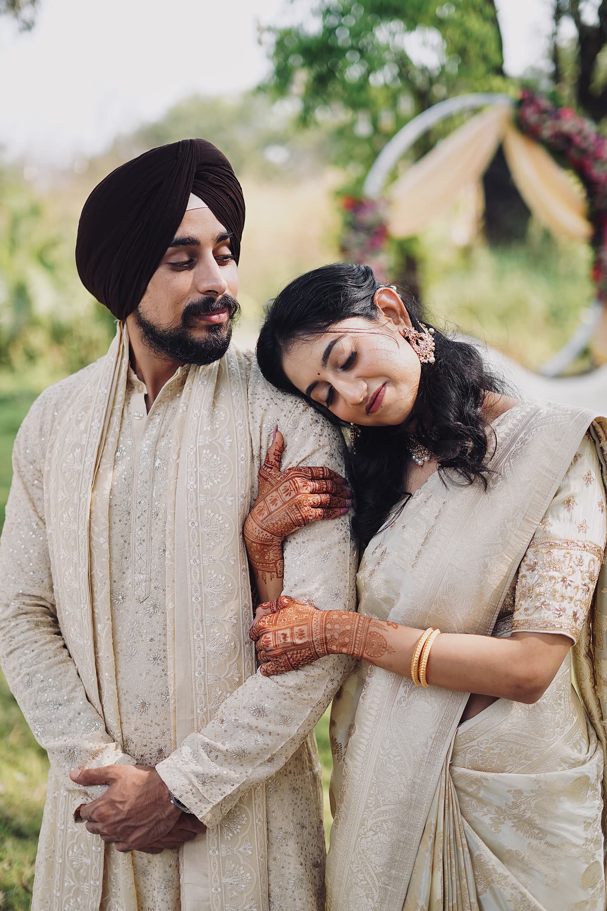 Her mehendi hands on his arm, head resting on his shoulder