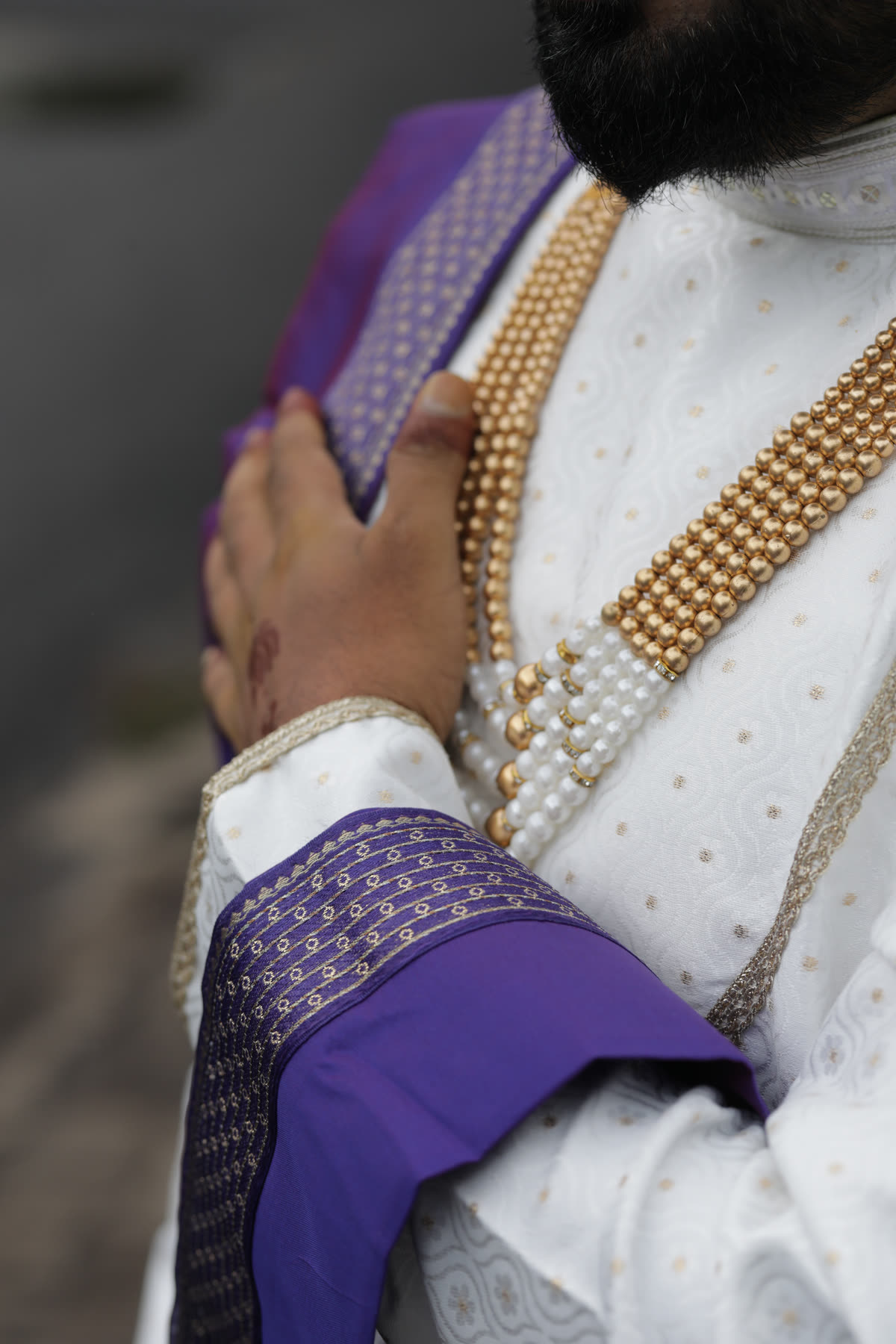 Her hand resting on his gold-beaded kurta