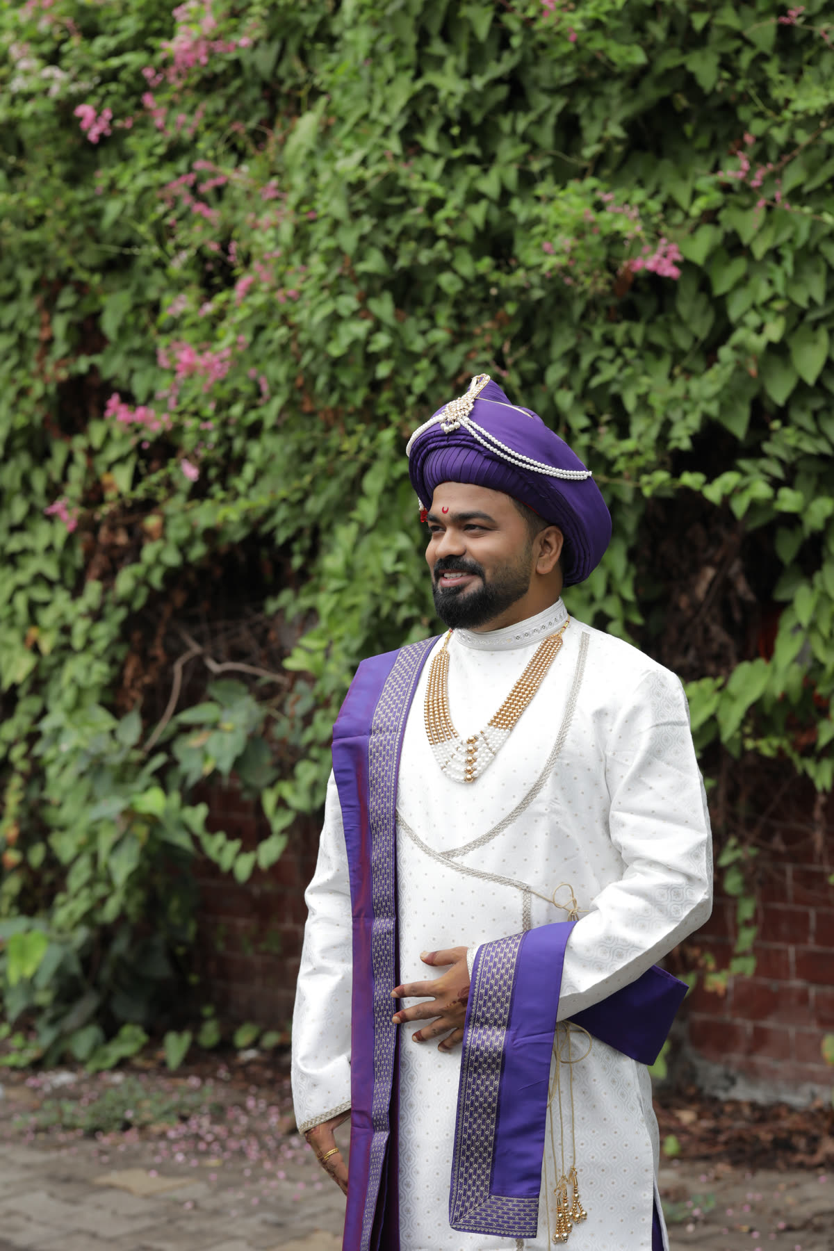 Groom in a purple pheta against bougainvillea
