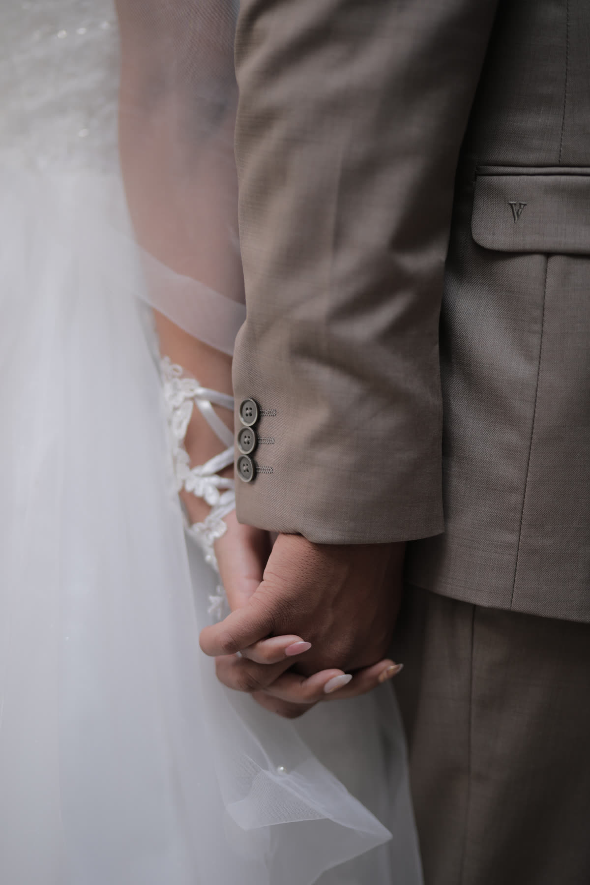 Hands held between a lace gown and a linen suit
