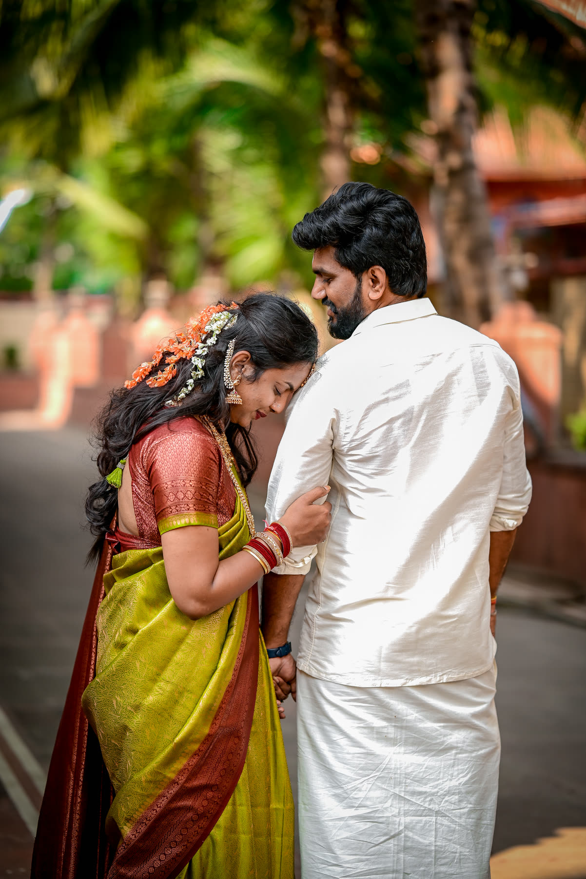 Leaning into his shoulder on a palm-lined path