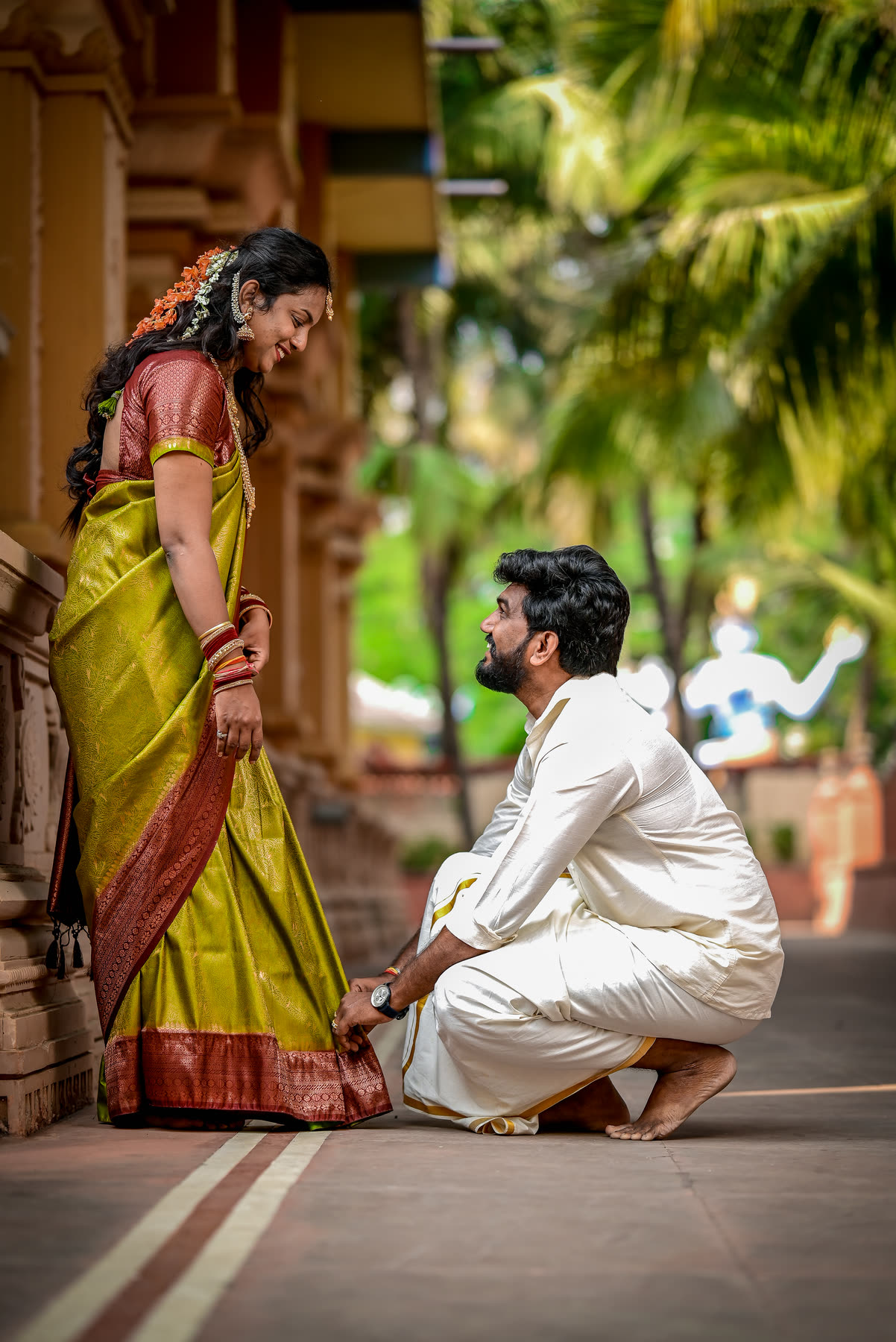 He kneels to fix her anklet in the temple corridor