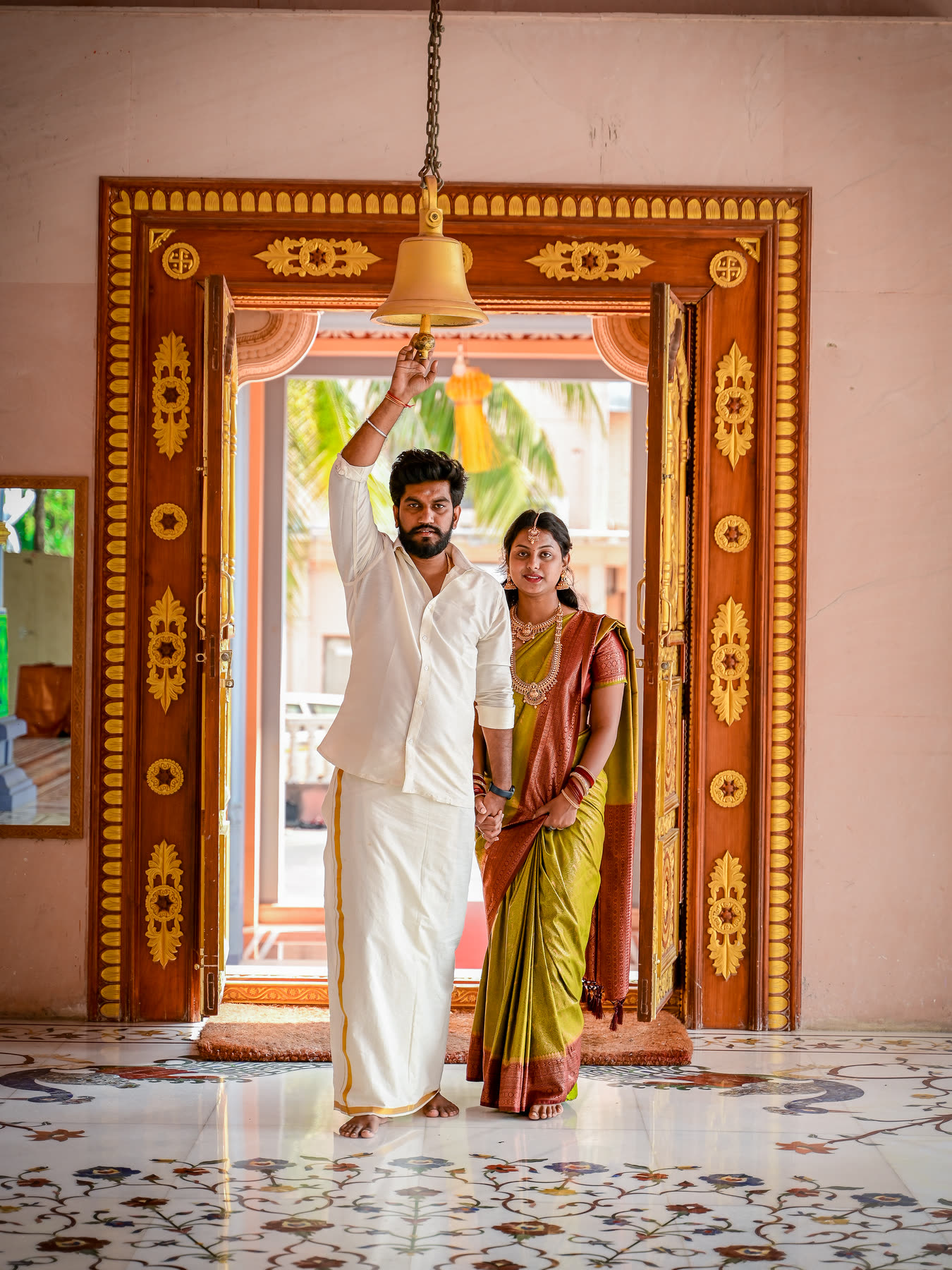 Ringing the temple bell in the carved doorway