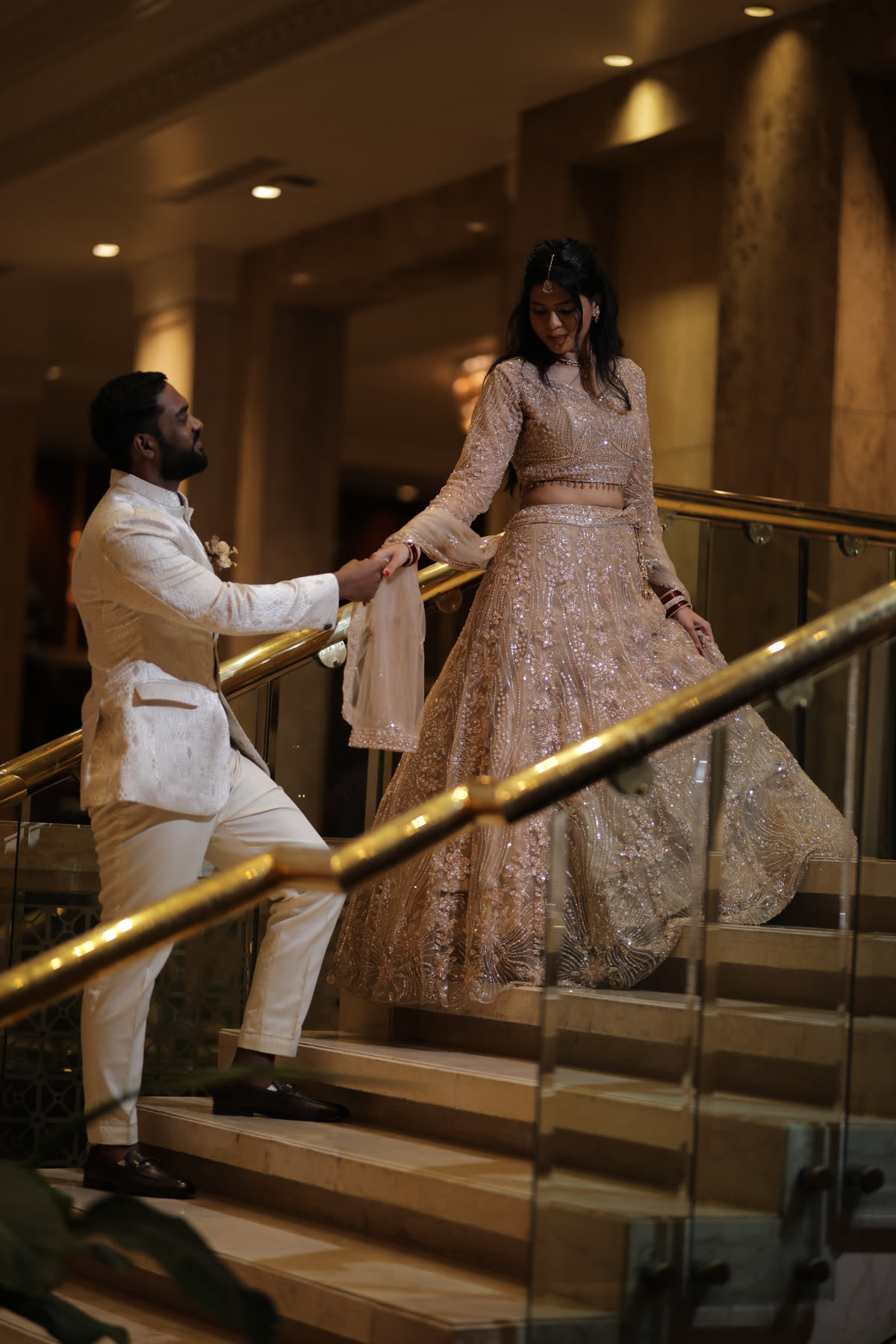 Leading her down the staircase in champagne tulle
