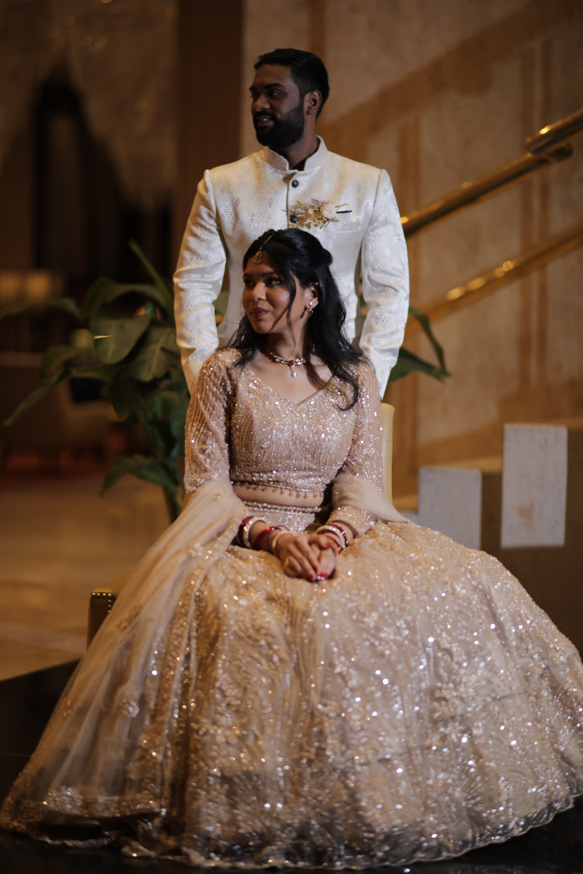 Seated in sequinned tulle, he stands behind